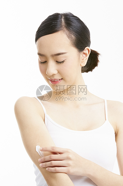 涂抹身体乳微笑的年轻女子图片