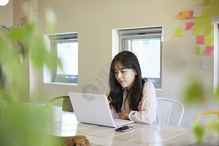 咖啡馆使用笔记本电脑的年轻女大学生图片