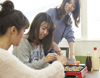 一起享用章鱼小丸子的年轻女孩图片