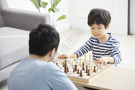 客厅里下棋拿起象棋的小男孩背景图片