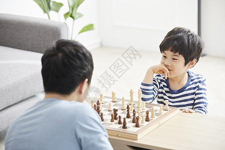 客厅里下棋小男孩看着父亲微笑图片