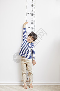 踮脚测量身高的小男孩图片