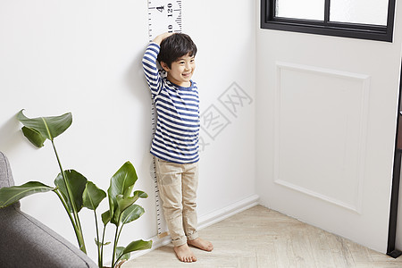韩国小男孩孩靠在墙上测量身高的小男孩背景