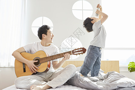 卧室里父亲弹吉他儿子拿着话筒唱歌图片