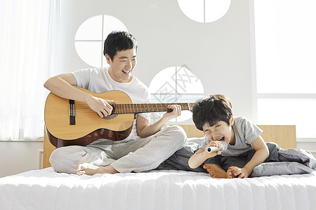 卧室里拿着吉他话筒开心的父子图片