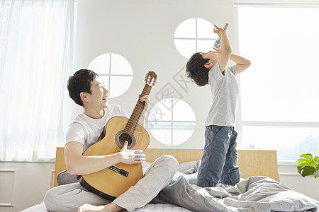 卧室里儿子拿着话筒唱歌父亲弹吉他图片