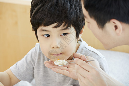 拿着勺子喂食小男孩的父亲图片