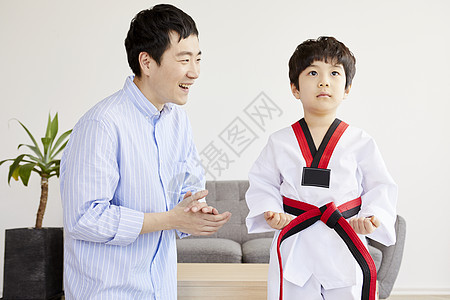 父亲微笑的看着穿着跆拳道服的儿子图片