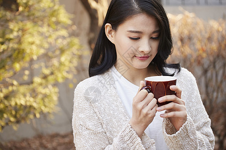 漂亮女孩子端着一杯咖啡在品尝图片