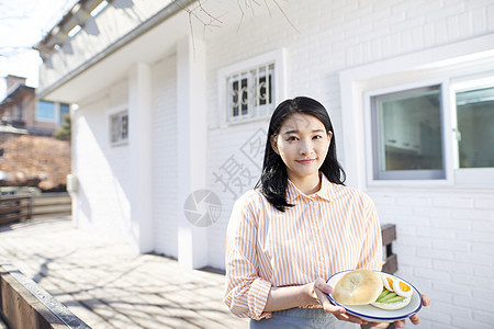 青年户外的年轻女人端着早餐图片