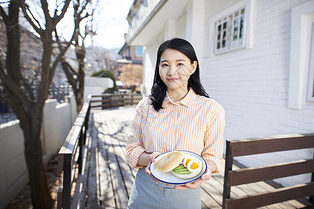 青年户外的年轻女人端着早餐图片