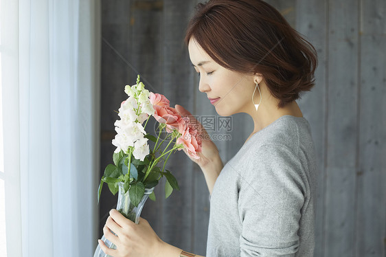 嗅闻鲜花香气的短发女子图片