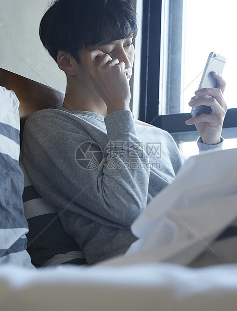 躺在床上看手机的商务男士图片