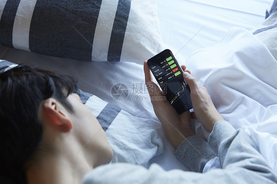 躺在床上使用手机的男士图片