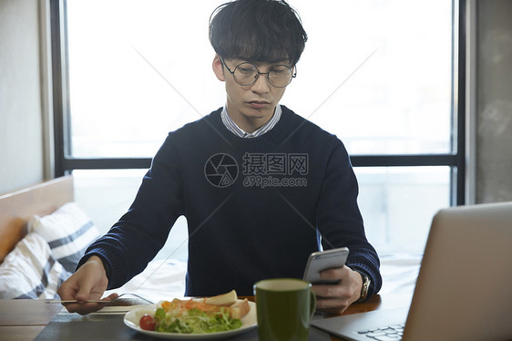 早餐看着手机的青年男子图片