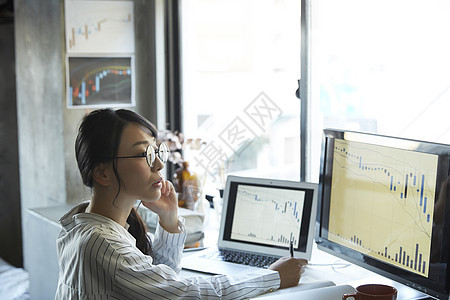 青年女子看着电脑上的股市信息图片