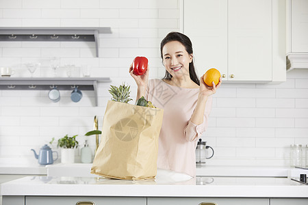 厨房里拿着蔬果微笑的女青年图片