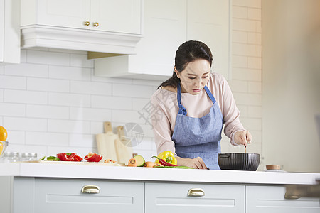 锅中制作料理的青年女子图片