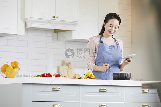 穿着围裙烹调食物的成年女子图片