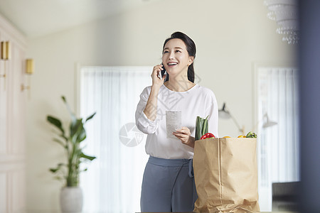 拿着小票接电话的成年女子图片