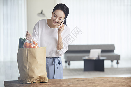 拿着蔬菜打电话的青年女性图片