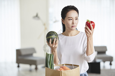 成年女子看着手上拿着的蔬菜图片