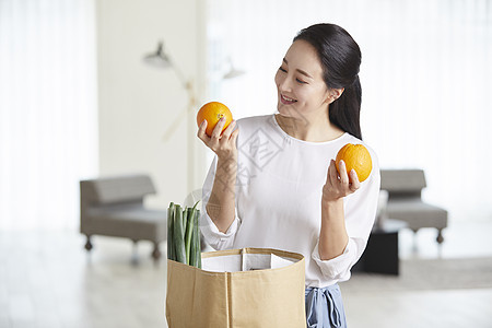 青年女子看着手上的橙子微笑图片