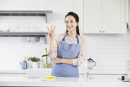 穿着围裙比手势微笑的青年女子图片