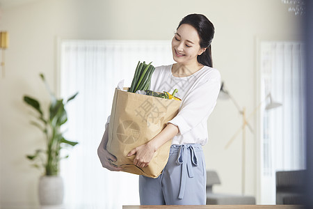 抱着一堆蔬果微笑的成年女子图片