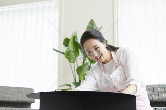 低头擦拭桌面的家庭主妇图片