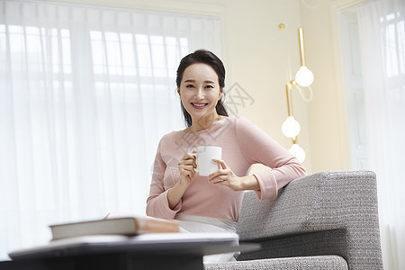坐在沙发上拿着咖啡的成年女子图片