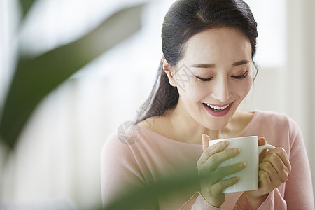 捧着杯子捧着咖啡低头微笑的女青年背景