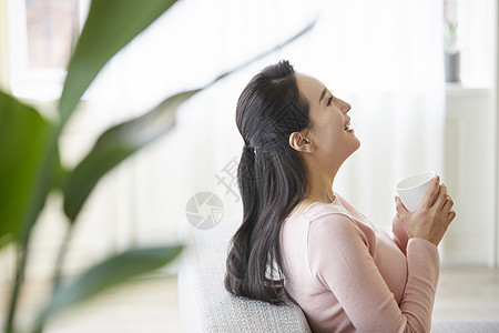 沙发上休息拿着水杯的青年女性图片