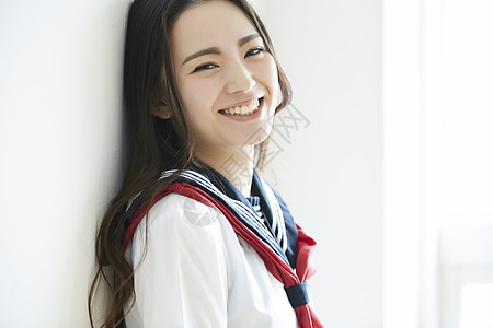 白墙女人靠在墙上转头微笑的少女背景