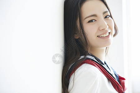 靠在墙上转头微笑的高中女生图片素材
