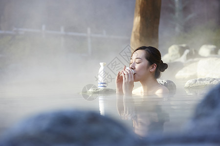 日本酒女人露天泡温泉喝清酒背景