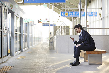 西装男子在看手机等地铁图片