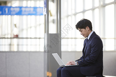 西装男子在地铁站用笔记本电脑图片