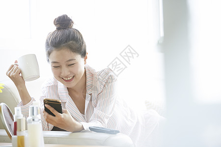 睡觉美容早晨看手机的俏皮女孩背景