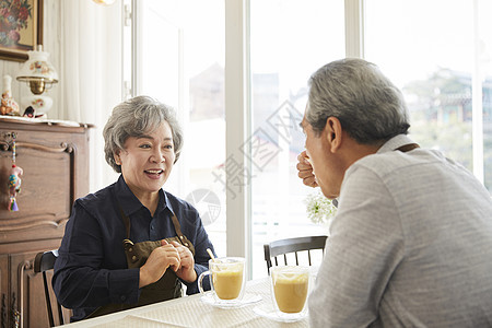 老夫妇戴围裙在室内一起休闲喝咖啡图片