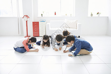 坐在地上用纸绘画的可爱小朋友们图片
