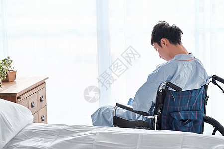 二十多岁沉思床坐在轮椅上的男人图片