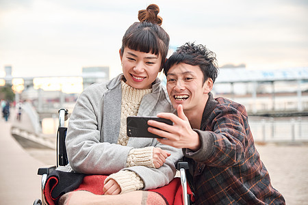 坐轮椅女人和拍照的男人图片