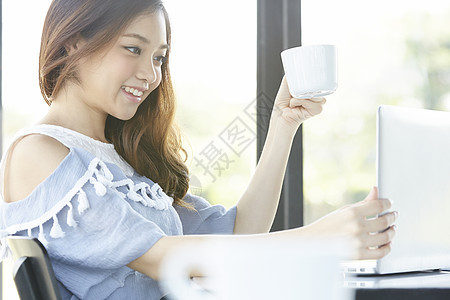 喝着咖啡看着电脑的年轻女子图片
