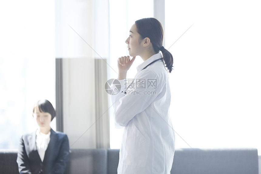 穿着白大褂扶着下巴思考的女性医生图片