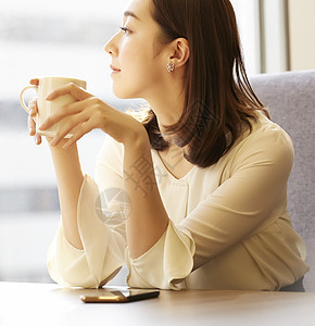 青年女性拿着咖啡看向窗外图片