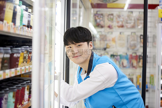 打开冰柜微笑的年轻店员图片