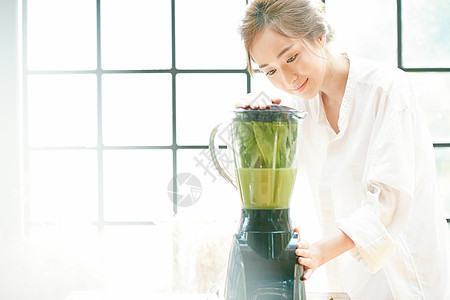 年轻女子榨蔬菜汁图片