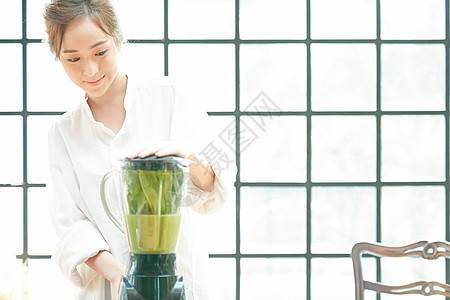 居家榨蔬菜汁的青年女子图片