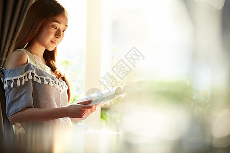 窗边阅读杂志的年轻女子图片